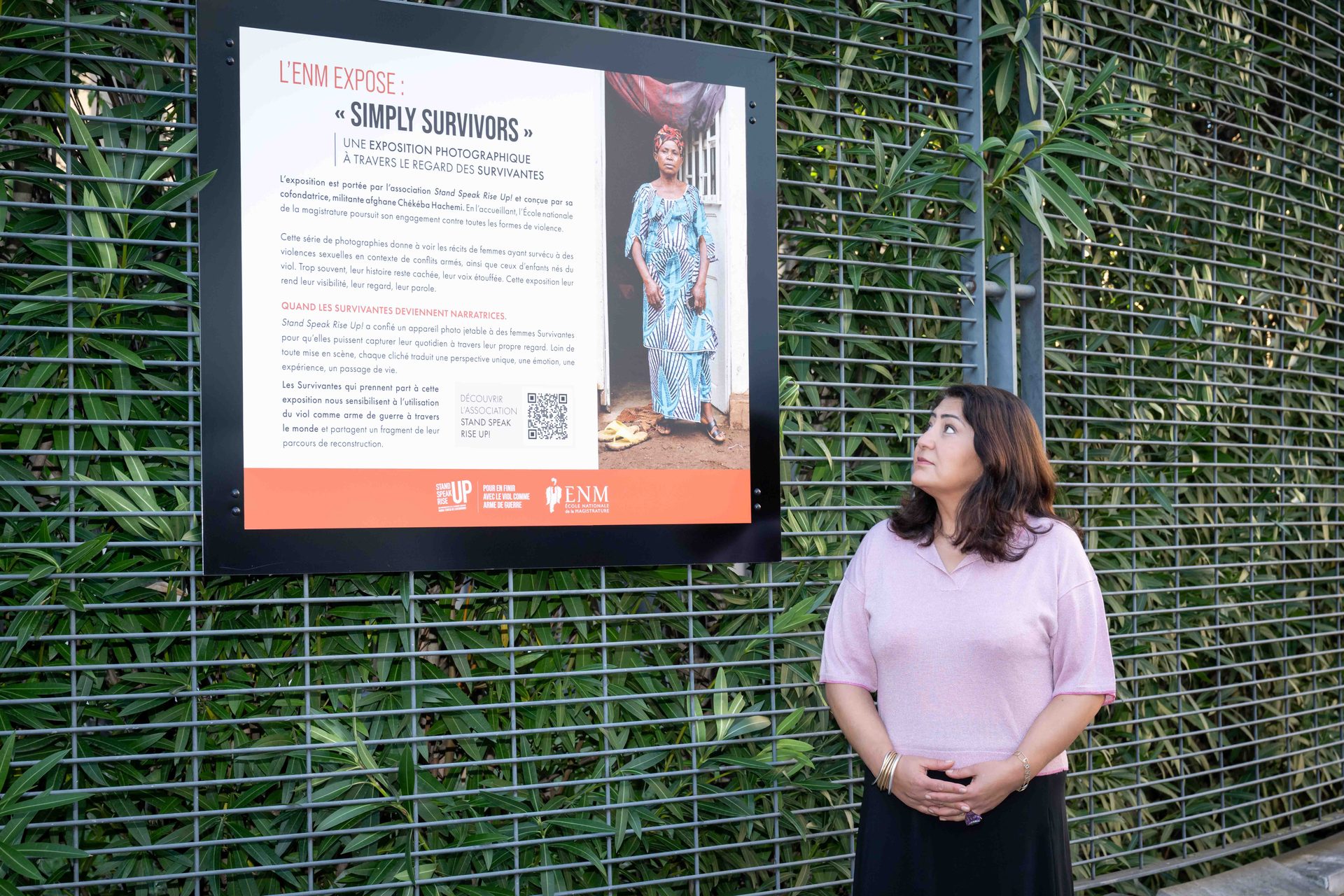 Chékéba Hachemi devant le panneau de présentation de l’exposition Simply Survivors à l’ENM