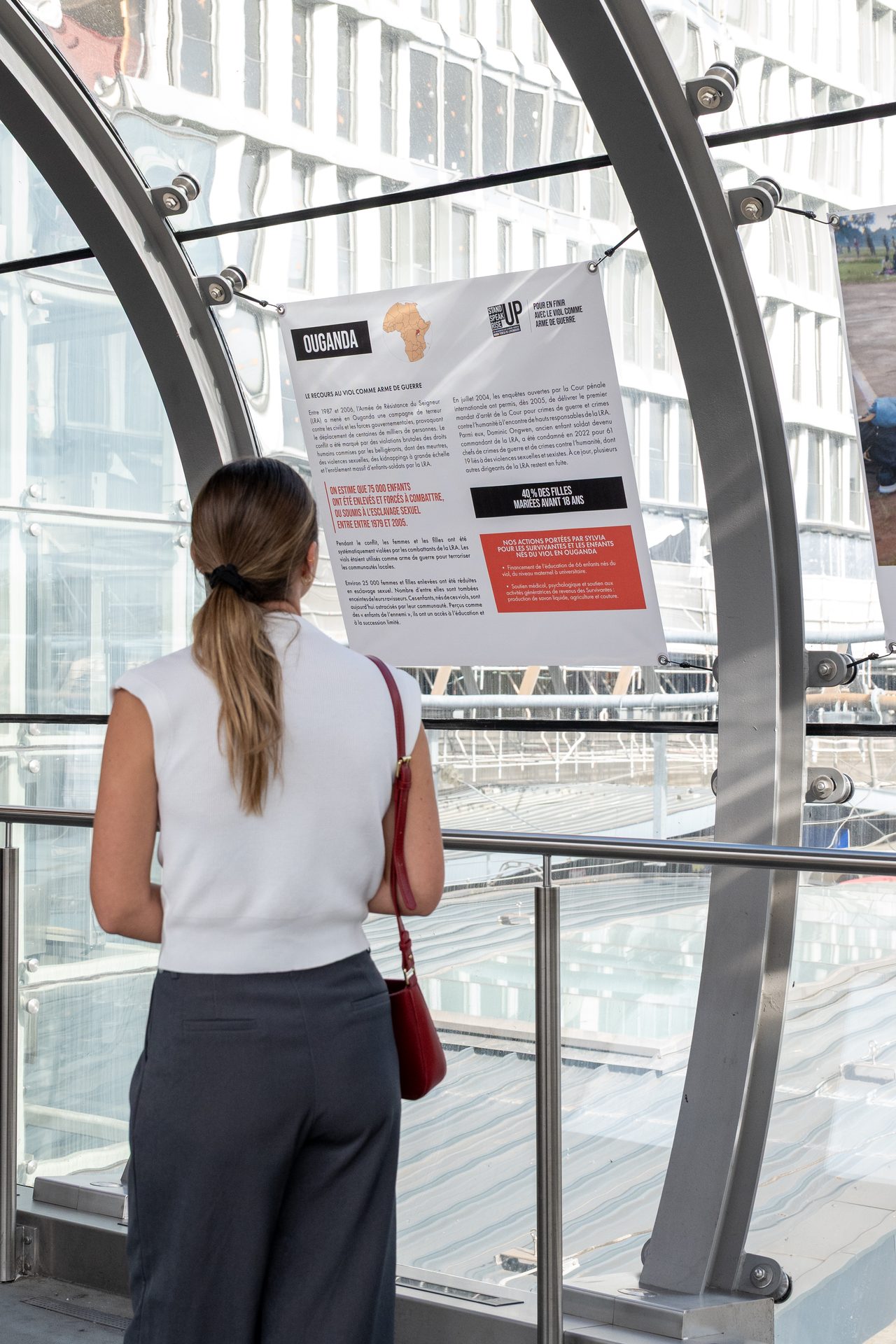 Une visiteuse lit un panneau de l’exposition Simply Survivors sur la passerelle de la gare